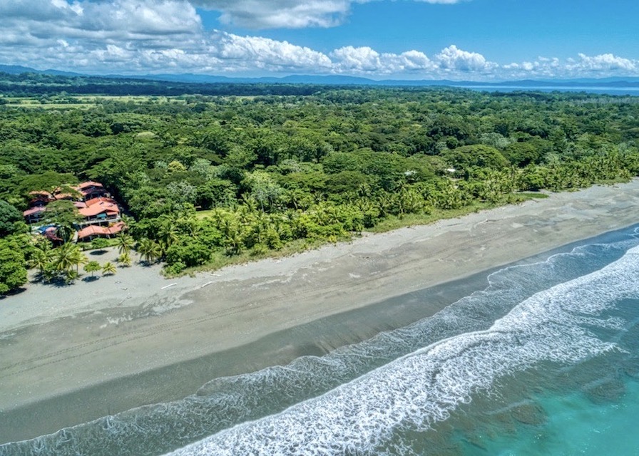 |Sunset over wide sandy beach near Osa Peninsula hotel |Beachfront resort with ocean views in Costa Rica|Hotel beachfront property viewed from ocean side |Outdoor seating and lounge area at Osa Peninsula hotel |Aerial view of hotel on Playa Preciosa in Osa Peninsula|Hotel property close to Puerto Jiménez and airport |Room overlooking Playa Preciosa from hotel balcony |Pathway from hotel to wide sandy beach |Palm trees and gardens surrounding hotel exterior |Drone view of beachfront hotel in Osa Peninsula |Guest kayaking in calm waters at Osa Peninsula beachfront hotel |Outdoor deck overlooking Pacific Ocean at sunset |Section of Playa Preciosa with few people ||Outdoor restaurant area facing Playa Preciosa |Front view of hotel showing access and parking area |Guest riding small waves near Playa Preciosa hotel |Scarlet Macaws flying above hotel property in Osa Peninsula|Guests swimming in calm tropical waters in front of hotel ||||||||||||||||||||||